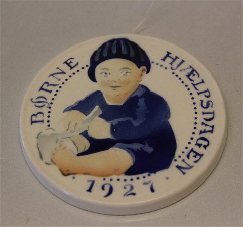 Royal Copenhagen Aluminia fajance Børnehjælpsplatte 1927 Barn trækker strømpe af Oscar Willerup 8,7 cm