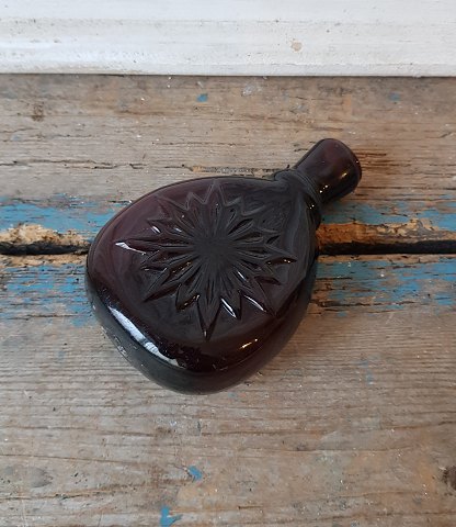 1800s pocket bottle in manganese colored glass with star in relief.