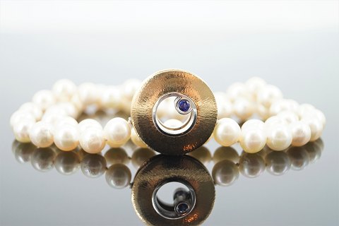 Ole Lynggaard; Luna clasp of 14k gold and white gold with a sapphire and a diamond