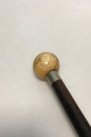 Antique walking stick with a well patinated head of turned ivory. Shaft of black painted hard wood. Collar as well as ferule of white metal. Heel of iron.
