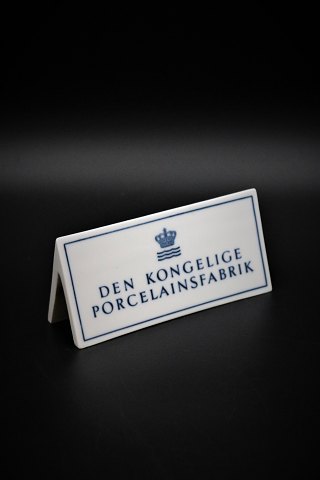 Gammelt forhandler skilt i porcelæn fra Royal Copenhagen "Den Kongelige Porcelænsfabrik" H:6cm. L:14cm.