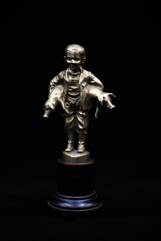 Gammel bronze figur af svinedrengen der holder 2 små grise under armen.Figuren stå på lille piedestal i træ. Højde: 14,5cm.