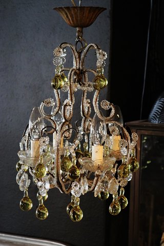 Dekorativ , gammel fransk lysekrone med klare glas prismer og glas kugler i en sart gul farve...