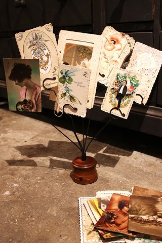 Old display for postcards, photos or business cards. The display is in black metal on a wooden base...
