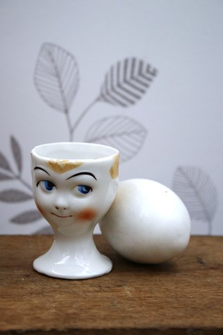Old egg cup from the 1930s in porcelain with a painted funny face.