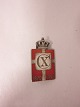 Royal batch made of Sterling silver 925S with red enamel motif of the DannebrogThis batch is made as a broochYear 1870-1940 is on as well as Christian XThe Silver smithy of Georg Jensen produced it in 1940-47