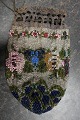 Antik PerletaskeTaske lavet som perlebroderi med smukt mønster bl.a. blomst/rosePosefacon med snøre i toppen for kombineret lukning og "hank"Tasken har mange perler og er derfor af en væsentlig vægtL: 17cm