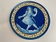 French faience plate / wall plaque with motif of blue girl with long braids in relief. The girl dances and plays music with castanets and tambourine, first half of the 20th century