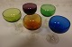 Smukke farvede glas Farvede kummer med klar glasfodDet præcise glasværk for produktionen har ikke kunnet identificeres med sikkerhedGrøn, blå, orange, mørk rød/aubergine og gulgrøn H: ca. 10cm