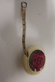 Målebånd i en runde holder, prydet med en rose, målebåndet trækkes udMålebåndet er fra den gode gamle tidPræget: "Dean Measure" Made in England