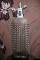 Decorative, old glass siphon with metal net from the 40s/50s, standing on a black bakelite tray...