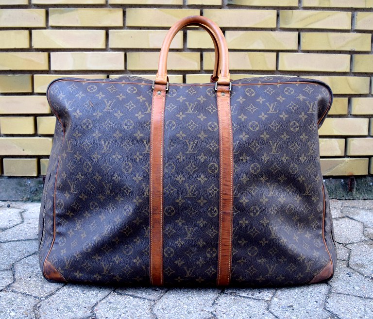Louis Vuitton: An "Alize" travel bag of monogram canvas with two handles of leather.