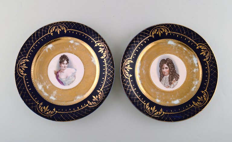 Two decorative plates in hand-painted porcelain with gold decoration. Motifs of Louis XIV and Madame Récamier. Vienna, circa 1900.