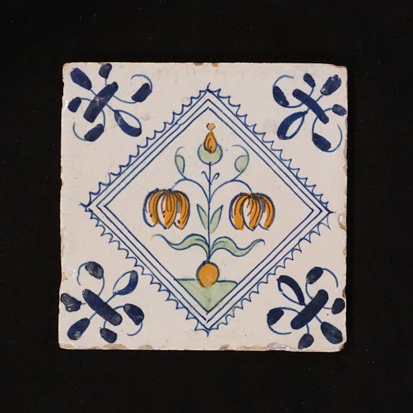A 17th century polychrome decorated Dutch tile with flowers. Circa 1620-40. Size: 13x13cm