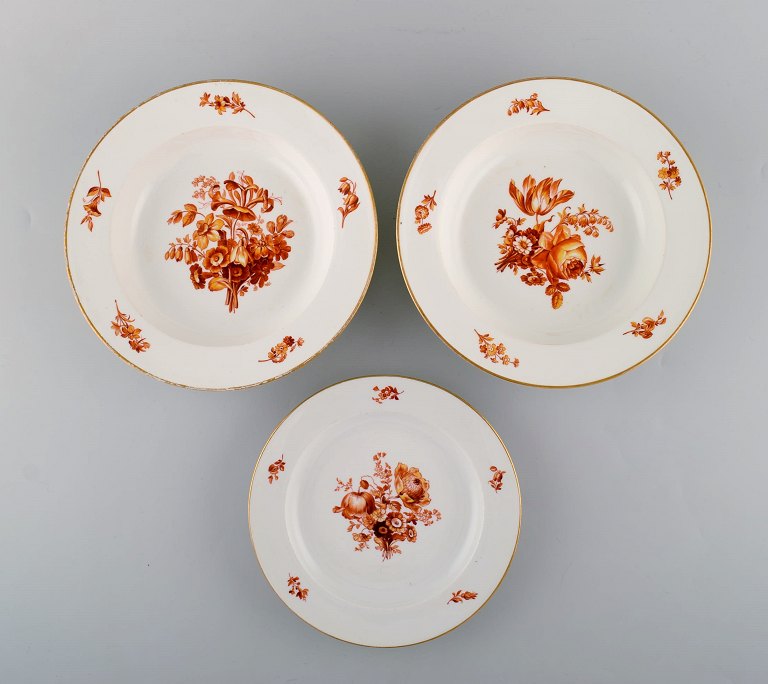 Three antique Meissen porcelain plates with orange hand-painted flowers. Two deep plates and one lunch plate. 19th century.