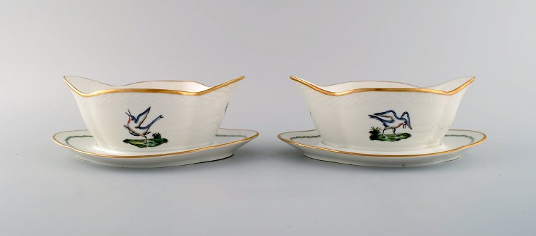 Two Royal Copenhagen sauce boats in hand-painted porcelain with bird motifs and gold decoration. Early 20th century.
