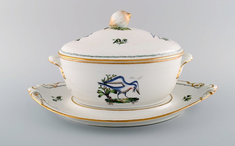 Stor Royal Copenhagen lågterrin med underfad i håndmalet porcelæn med fuglemotiver og gulddekoration. Tidligt 1900-tallet. 