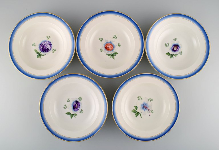 Five antique Royal Copenhagen deep plates in hand-painted porcelain with flowers and blue border with gold. Model number 592/9049. Late 19th century.