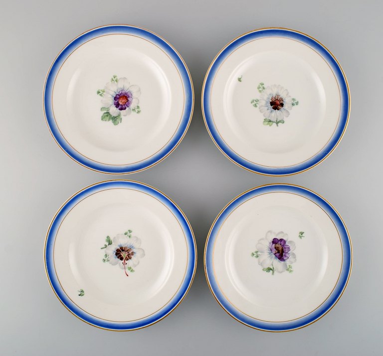 Four antique Royal Copenhagen plates in hand-painted porcelain with flowers and blue border with gold. Model number 592/9052. Late 19th century.