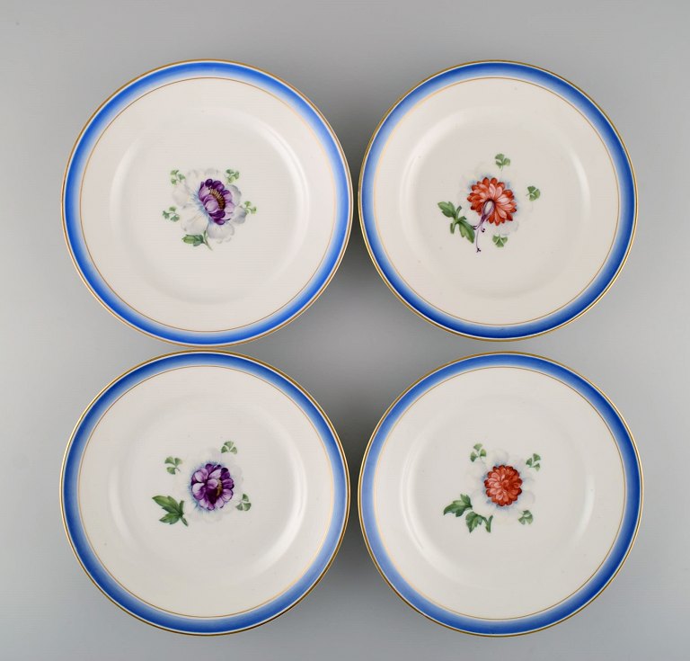 Four antique Royal Copenhagen plates in hand-painted porcelain with flowers and blue border with gold. Model number 592/9051. Late 19th century.