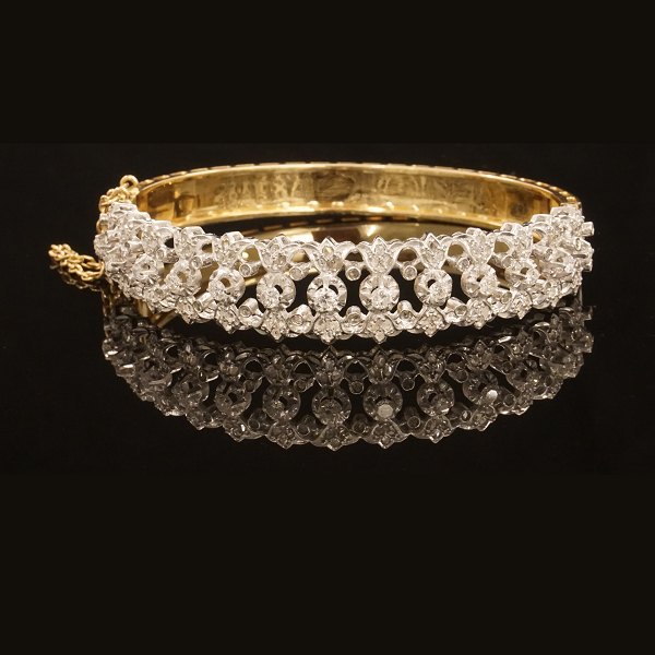 Armring i 18kt guld prydet med 13 diamanter. Skjult lås med sikkerhedskæde. Indv. mål: 5,6x6cm.