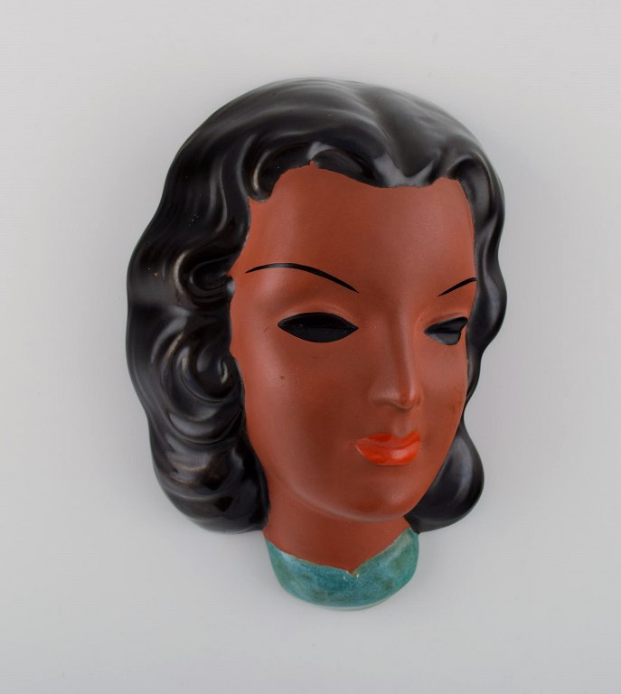 Goldscheider, Østrig. Art deco kvindeansigt i håndmalet glaseret keramik. Dateret 1953.