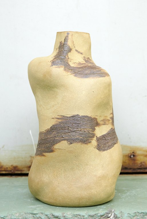 Christina Muff, dansk samtidskeramiker (f. 1971). Flaskeformet skulpturel vase i gyldent stentøjsler med begitning af ler fra Frederiksberg i København. Vasen er håndlavet og Leret er malet på i hånden med store penselsstrøg.