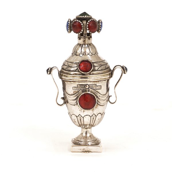 Hovedvandsæg i sølv. Christian Haas, 1795-1821, Haderslev. Født i Tønder. Prydet med talrige flusser i røde, blå og grønne farver. H: 9,1cm. V: 53,5gr