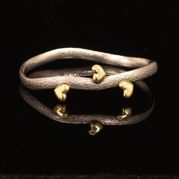 Michale Weihe: Oval armring i sterlingsølv med tre hjerter udført i 18kt guld. Indv. mål: 5,5x6,4cm. B: 0,6cm. V: 32gr