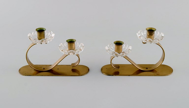 Gunnar Ander for Ystad Metall. Two candlesticks in brass and clear art glass shaped like flowers. 1950s.