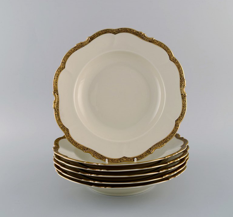 KPM, Berlin. Seks Royal Ivory dybe tallerkener i cremefarvet porcelæn med gulddekoration. 1920