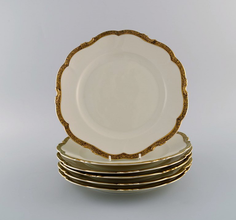 KPM, Berlin. Seks Royal Ivory middagstallerkener i cremefarvet porcelæn med gulddekoration. 1920