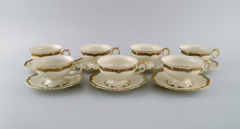 KPM, Berlin. Syv Royal Ivory tekopper med underkopper i cremefarvet porcelæn med gulddekoration. 1920
