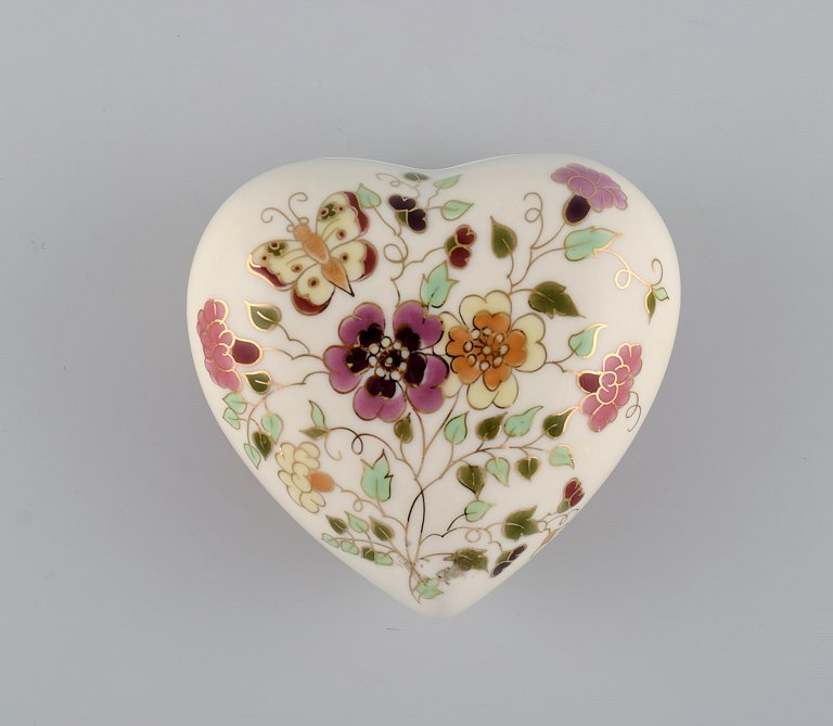 Heart-shaped Zsolnay lidded box in cream-colored porcelain with hand-painted flowers, butterflies and gold decoration. Late 20th century.