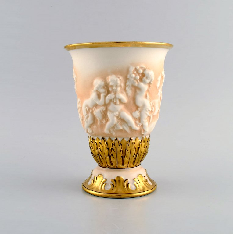 Capodimonte, Italien. Antik porcelænsvase med putti i relief og håndmalet gulddekoration. Tidligt 1900-tallet.