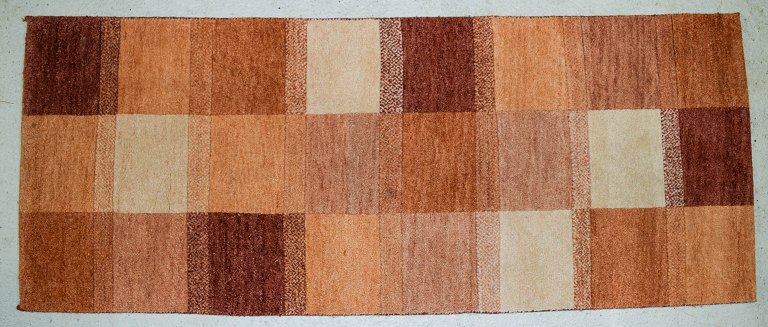 Milford, Sverige, tæppe i ren uld. Geometriske felter i røde, orange, og hvide nuancer. 1970