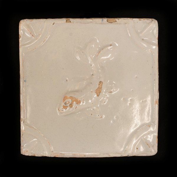Lyst glaseret reliefflise med motiv i form af fisk. Fremstillet på Blåtårn Fabrikken, København, ca. år 1740. Mål: 13x13cm