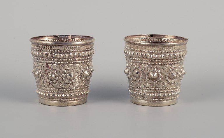 Chinese silversmith. Two small goblets richly decorated in relief with flowers and ornaments.