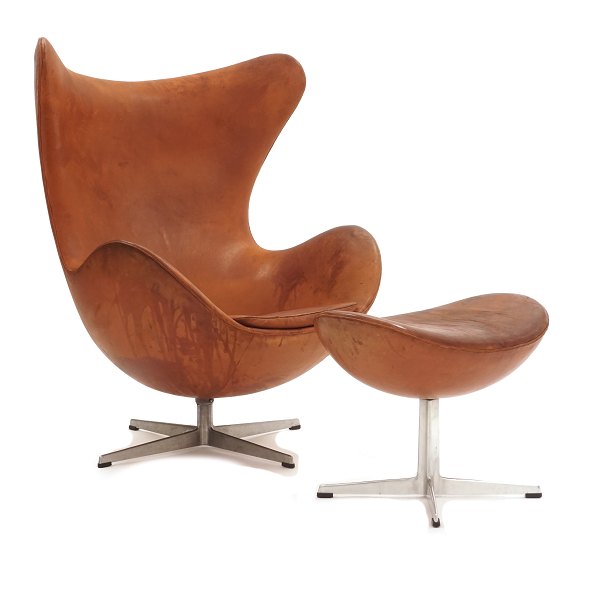 Arne Jacobsen Ægget i cognac farvet læder med tilhørende fodskammel. Begge på profileret firpas fod. Læder med patina