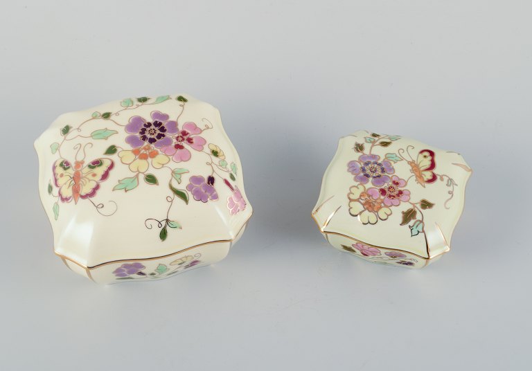 Zsolnay, Hungary, two lidded jars in porcelain hand-painted with flower motifs and insects on a cream-colored background.