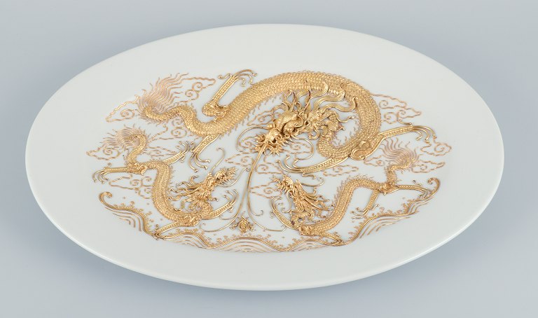 Stort ovalt porcelænsfad i Versace-stil, drager i relief.Dekoreret med guldbelagt metal.