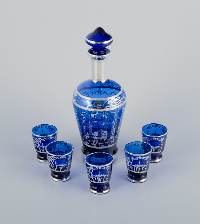Venice, Italy. A liqueur set in blue glass consisting of a decanter and five cups. Hand-painted with silver decoration featuring Venice motifs.