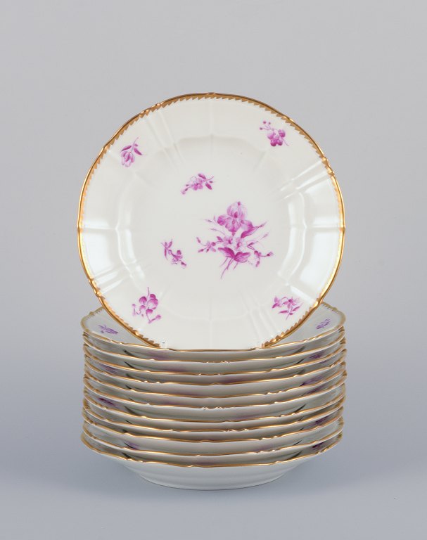 Bing & Grøndahl, Denmark. A set of twelve small plates with flower decorations in purple and gold trim. Hand-painted.