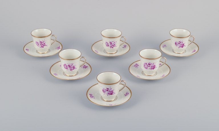 Bing & Grøndahl, Danmark. Et sæt på seks mokkakopper med tilhørende underkopper dekoreret med blomstermotiver i purpur og guldkant. Håndmalet.