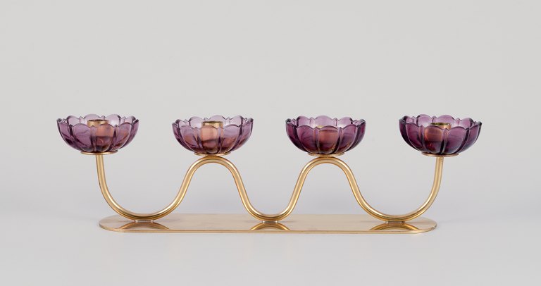Gunnar Ander for Ystad Metall, Sweden.Four-armed candle holder in brass with purple art glass shaped like flowers.