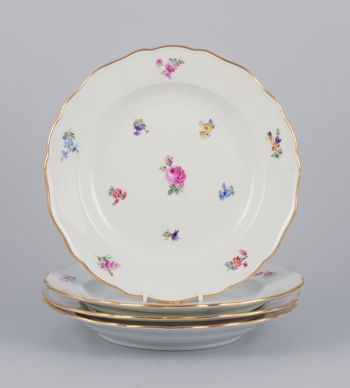 Meissen, Tyskland. Et sæt på fire middagstallerkner i porcelæn håndmalet med forskellige polykrome blomstermotiver samt guldkant.