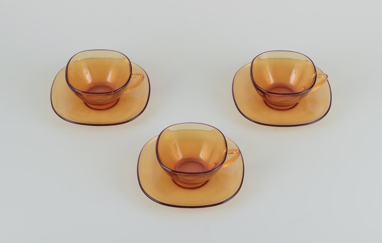 Vereco, Frankrig. Et sæt på tre kaffekopper med tilhørende underkopper i ravfarvet glas. Modernistisk design.