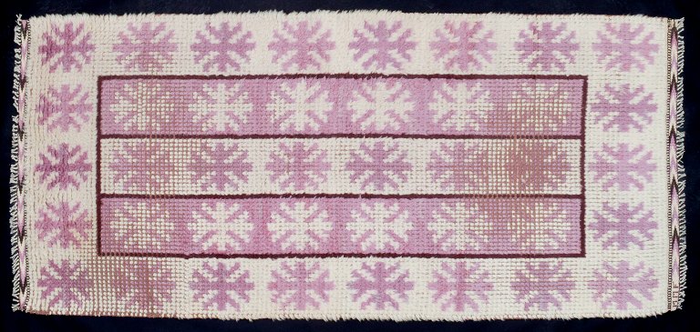 Märta Måås-Fjetterström (1873–1941). Swedish textile designer.Unique handwoven wool rya carpet in a modernist design. Pink and white in a geometric pattern.