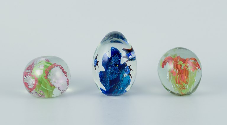 Scandinavian glass artist. Set of three paperweights in art glass. Flower motifs and more embedded in the glass. Handmade.