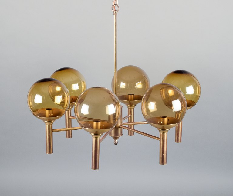 Sv. Mejlstrøm, dansk designer. Lysekrone af messing, seks arme med kuppelformede skærme af ravfarvet glas.